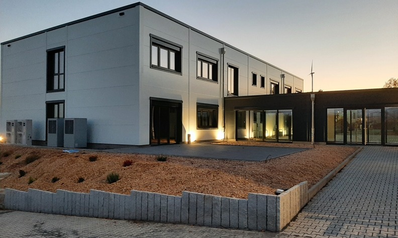 D.W.I. Betriebsgebäude in Weidenberg – Rückansicht in der Abenddämmerung mit moderner weißer Fassade und gepflastertem Vorplatz