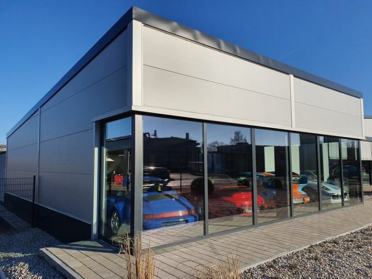 Repräsentative Verkaufsfläche eines Autohauses hinter der Glasfassade einer Stahlhalle