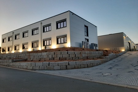Zweigeschossiges Bürogebäude in Stahlbauweise mit angebauter Halle in der Abenddämmerung